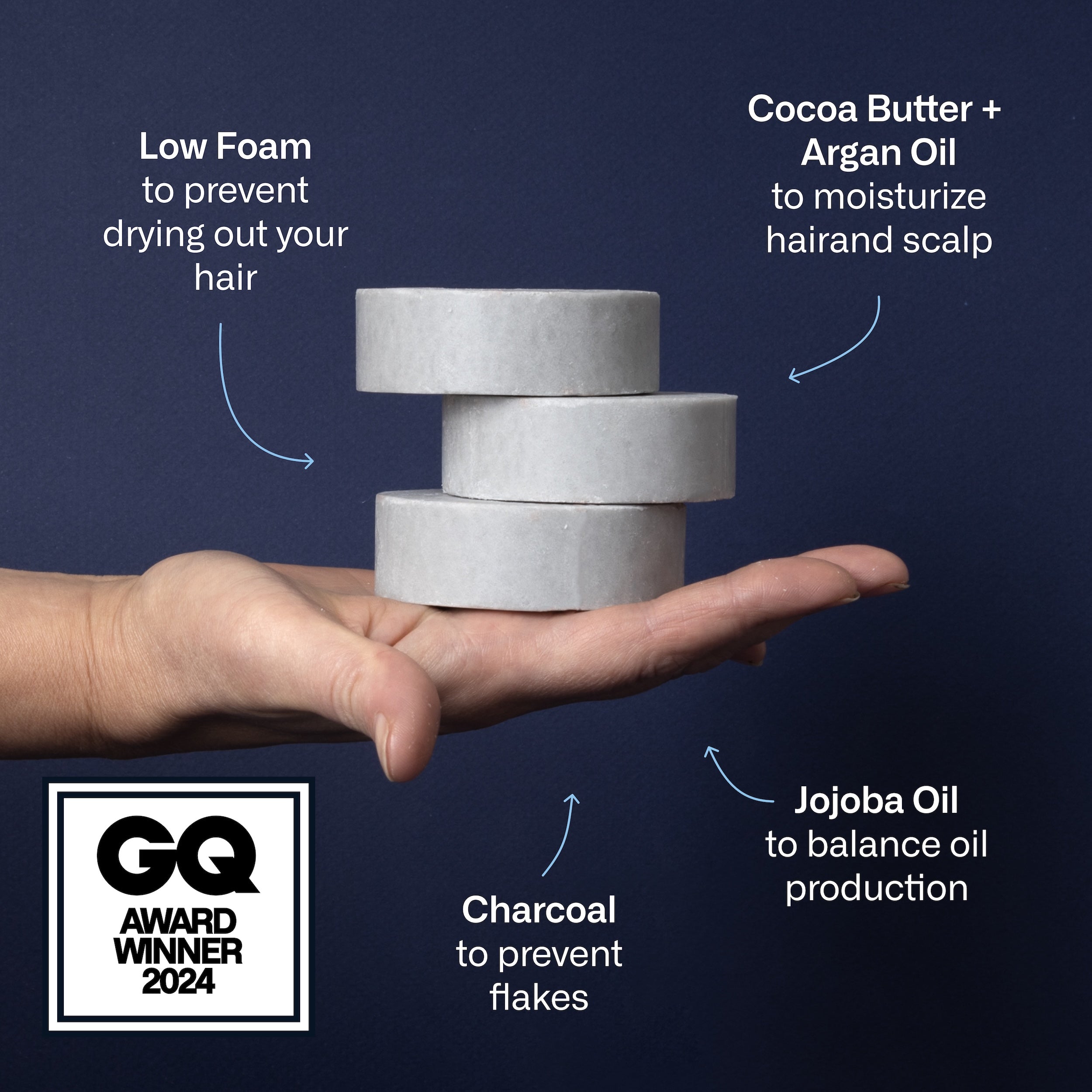 Hand holding three stacked round charcoal shampoo bars against dark background, GQ AWARD WINNER 2024 badge visible