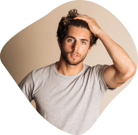 A man with tousled hair touching his head, reflecting concerns about hair care.