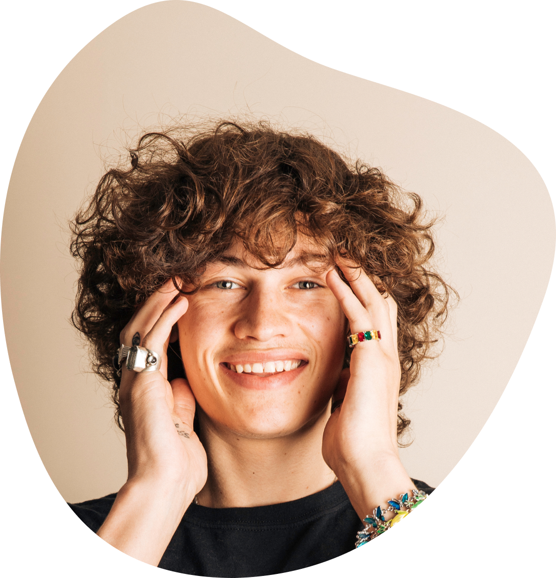 A man with curly, long hair running fingers through his hair and smiling.