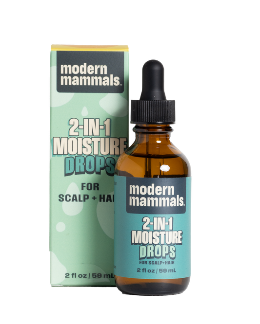 Front view of 2 fl oz amber glass dropper bottle of 2‑in‑1 Moisture Drops showing dropper cap and label next to mint‑green product box