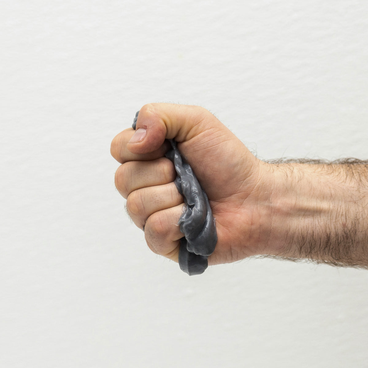 Hand squeezing charcoal-gray clay-like hair wash paste