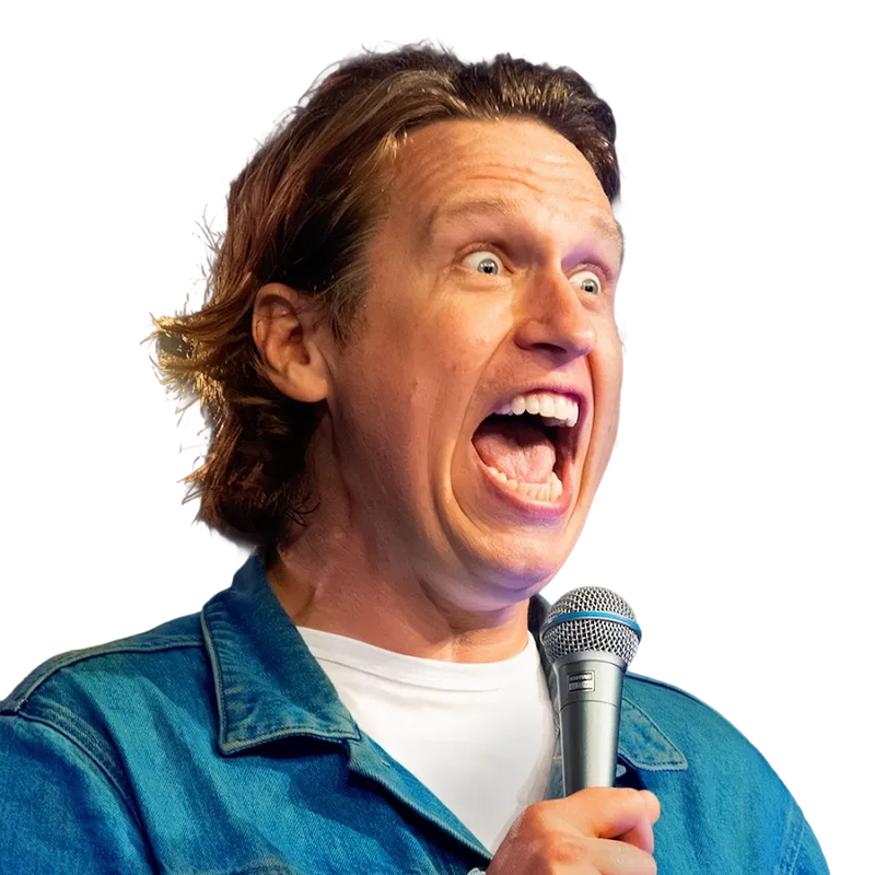 Comedian on stage holding a microphone, mouth open mid-speech