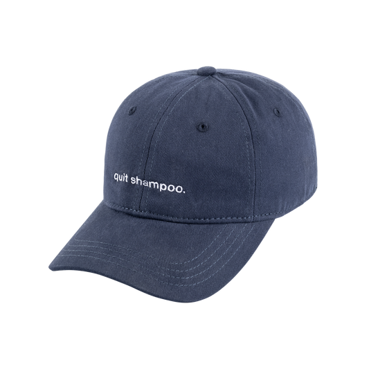 Three-quarter view of Modern Mammals Hat showcasing embroidered phrase ‘quit shampoo.’ on the front with white background